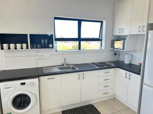 une cuisine blanche avec un évier et une machine à laver dans l'établissement Shine house, à Somerset West
