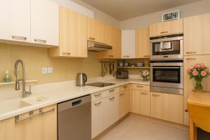 a kitchen with wooden cabinets and stainless steel appliances at Appartement Premium 100 m2 avec Jardin Privé Plage et Centre à 400 m in Deauville
