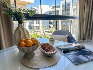 a table with a bowl of oranges and a vase at Апартаменты Qoople Triumph 17 рядом с пляжем Клеопатры in Alanya