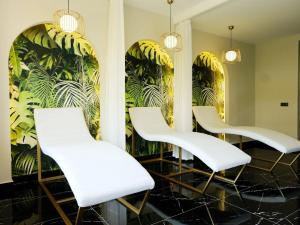 four white chairs in a waiting room with plants on the wall at Апартаменты Qoople Triumph 17 рядом с пляжем Клеопатры in Alanya