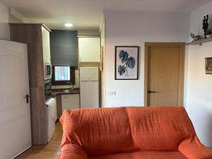 Una sala de estar con un sofá naranja en una cocina. en Casa Rural Antikaria, en Antequera