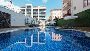 a swimming pool in a building with an umbrella at Апартаменты Qoople Triumph 17 рядом с пляжем Клеопатры in Alanya