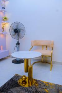 a table and a chair and a fan in a room at Gpark Luxury Homes And Apartments in Sagamu