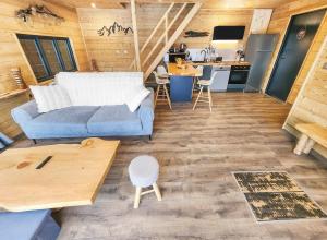 a living room with a blue couch and a kitchen at Chalet Cocoon en lisière de forêt, avec grande terrasse, et vue 'waouh' in Allevard