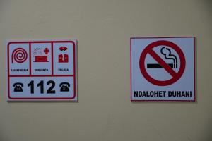 deux signaux sur un mur avec un signal non-fumeurs dans l'établissement Balkan Hostel, à Tirana