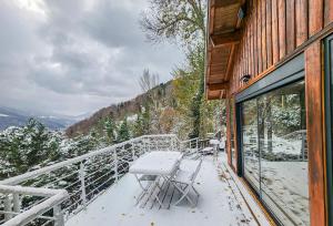 a balcony of a house with a table and chairs at Chalet Cocoon en lisière de forêt, avec grande terrasse, et vue 'waouh' in Allevard