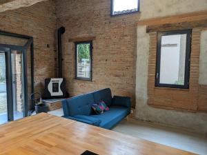a living room with a blue couch and a brick wall at GITE La GRANGE in Launac