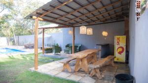 a wooden picnic table and benches under a pergola at Casa Bosque da Serra in Crato