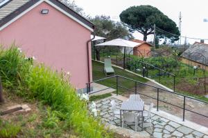 Una casa rosa con dos mesas y sillas en un patio. en La casa tra gli ulivi, en Génova