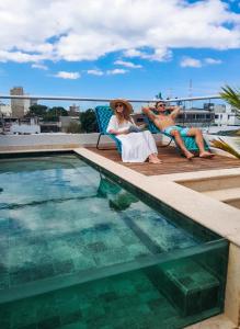two people sitting in chairs next to a swimming pool at Hotel Casa de la Acequia in Santa Marta +74 photos