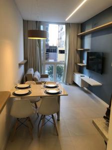 a living room with a table and chairs and a television at Baltico302 in Capão da Canoa