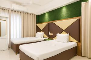 een kamer met 2 bedden en een groene muur bij Baral White Rose Hotel in Dhaka