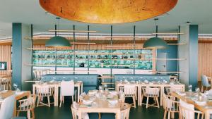 a restaurant with tables and chairs and a bar at Pedras do Mar Resort & Spa in Fenais da Luz
