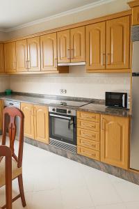 MarinaMar Camariñas في كامارينياس: مطبخ بدولاب خشبي وموقد وكرسي