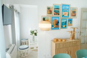 a living room with a wall with pictures on it at Maïmo Cosy Appartement rénové Centre Ville 300m plage, Clim, Parking in Sainte-Maxime +24 photos