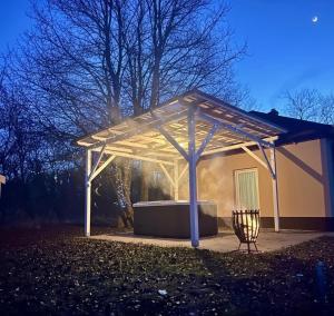 a white pergola with a bench under it at Varázslakos Tanya in Soltvadkert