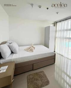 una camera bianca con un letto e una grande finestra di Bernwood Tower 2BR-707 a Città di Iloilo