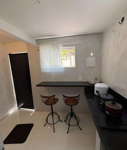 a kitchen with a black counter and stools in it at Pé na areia Geriba Buzios 2 in Búzios