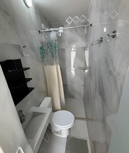 a white bathroom with a toilet and a shower at Pé na areia Geriba Buzios 2 in Búzios