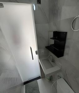 a white bathroom with a sink and a toilet at Pé na areia Geriba Buzios 2 in Búzios