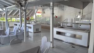 a kitchen with white tables and white chairs at Le Joyeux 