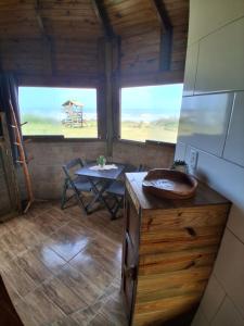 Zimmer mit einem Tisch und 2 Fenstern in einer Hütte in der Unterkunft Bangalô Pé na Areia in Imbituba