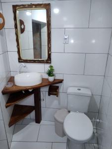 ein Badezimmer mit Toilette, Waschbecken und Spiegel in der Unterkunft Bangalô Pé na Areia in Imbituba