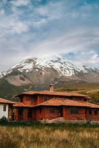 a building with a snow covered mountain in the background at Taytapak Wasi in Riobamba