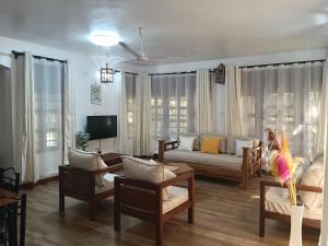a living room with a couch and chairs and a tv at Pearl Homes in Ukunda