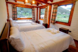 two beds in a room with two windows at Taytapak Wasi in Riobamba