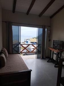 a bedroom with a bed and a door to a balcony at Casas no Centro Histórico de Garopaba in Garopaba