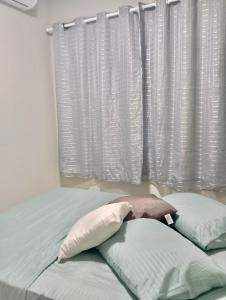 ein Bett mit zwei Kissen vor einem Fenster in der Unterkunft Flat Coqueirinho in Conde + 18 Fotos