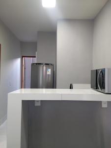 eine Küche mit einer Arbeitsfläche, an der eine Mikrowelle und ein Kühlschrank angebracht sind in der Unterkunft Flat Coqueirinho in Conde