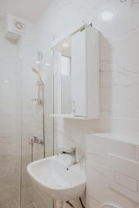 a white bathroom with a sink and a mirror at Gallus Inn in Aleksinac +10 photos