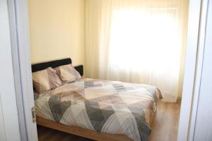 a bedroom with a bed with a comforter and a window at Ezerkrasta Apartment in Liepāja