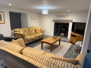 a living room with two couches and a fireplace at Tregue Cottage in Camelford