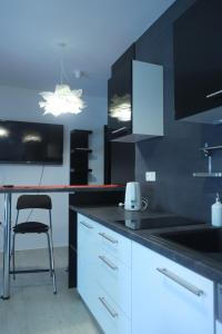 a kitchen with white cabinets and a black counter top at Apartman Gala in Čakovec
