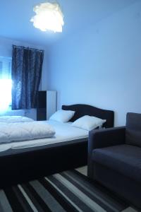 a bedroom with a bed and a couch with a blue light at Apartman Gala in Čakovec
