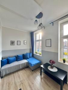 a living room with a blue couch and a table at Przy Parku Róż II in Chorzów