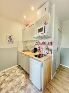 a small kitchen with white cabinets and a microwave at Przy Parku Róż II in Chorzów