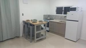 a small kitchen with a white refrigerator and a table at ChicPDD in Punta Del Diablo