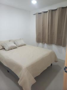 een bed in een witte kamer met een raam bij ChicPDD in Punta Del Diablo