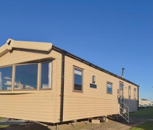 a large wooden caravan parked in a yard at The Eden - Sleeps 8 Pet Friendly Free Wi-Fi With Patio & Hub Passes Camber Sands Cosy Spacious Modern 8 Berth Caravan in Camber