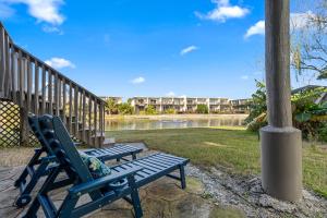 due panchine blu sedute accanto a un fiume con un edificio di Forever Summer a Oriole Beach