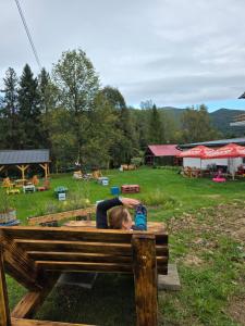 韦特利纳Przystanek Smerek的一名女子躺在长椅上，手里拿着一台相机。