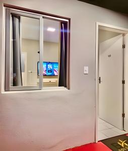 a room with a window and a door with a television at #FInALdeSeMaNaTop em Matinhos a 50m da PrAiA in Matinhos