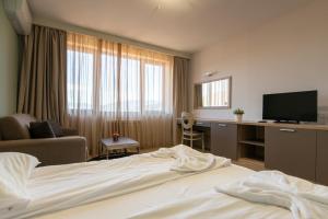 a hotel room with a bed and a desk with a television at Hotel LaCasa Tsigov Chark in Batak +19 photos