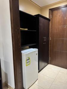 ein kleiner weißer Kühlschrank in einem Raum mit einer Tür in der Unterkunft Jazirat Al Balad in Muzdalifah