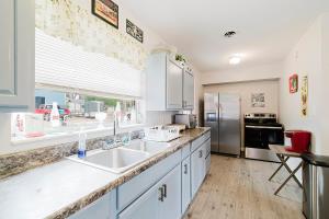 uma cozinha com armários brancos e uma grande janela em Little red house with vintage, retro feel to it! em Ocala