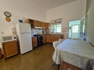 a kitchen with a table and a white refrigerator at Oasis in Villa Anizacate